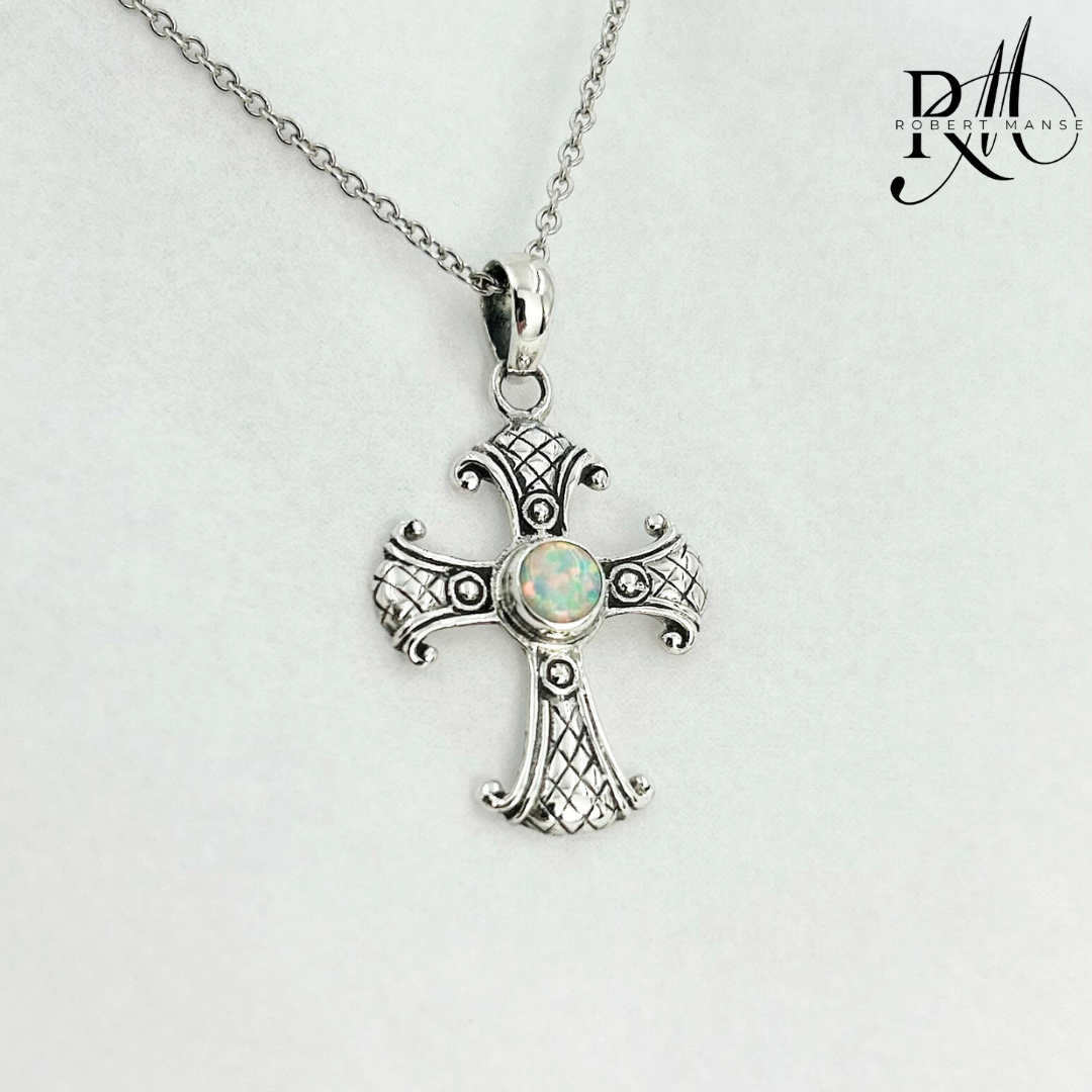 Silver cross pendant with opal stone on a chain against a light gray background