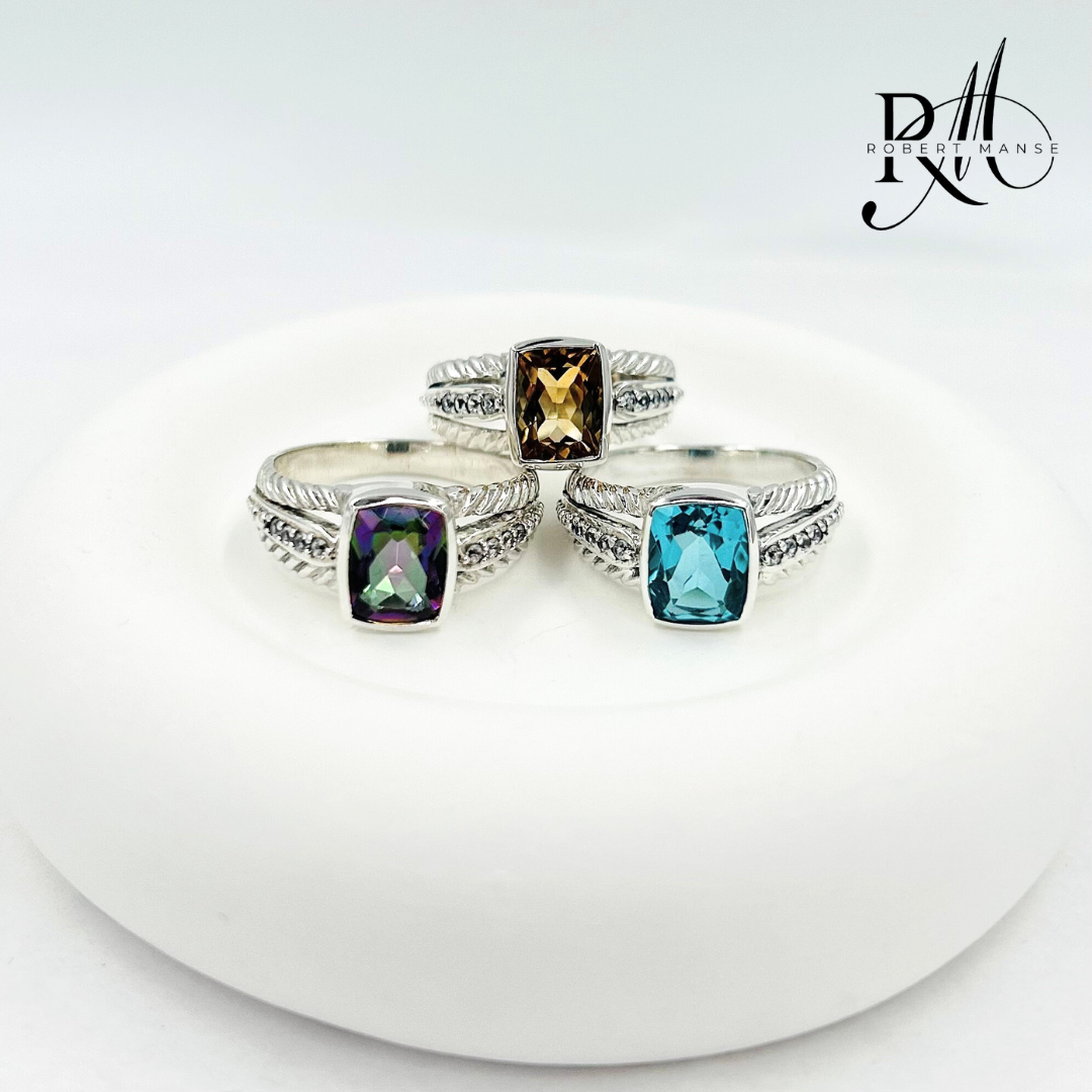 A set of three sterling silver rings, each featuring a different colored gemstone in a cushion cut setting, surrounded by smaller round white zircon stones. The rings are displayed on a white surface.