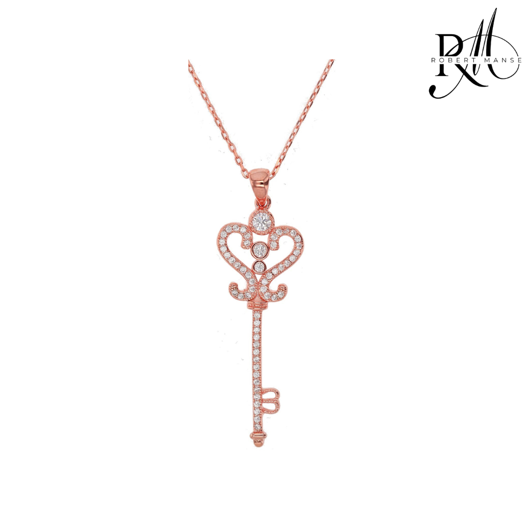 Rose gold key-shaped pendant necklace on a white background with 'Rivale' branding.