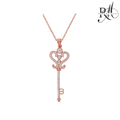 Rose gold key-shaped pendant necklace on a white background with 'Rivale' branding.